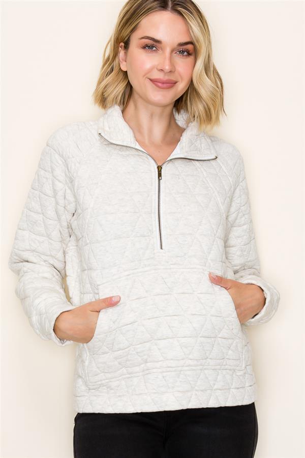 Woman wearing a ash grey quilted jacket against a plain background