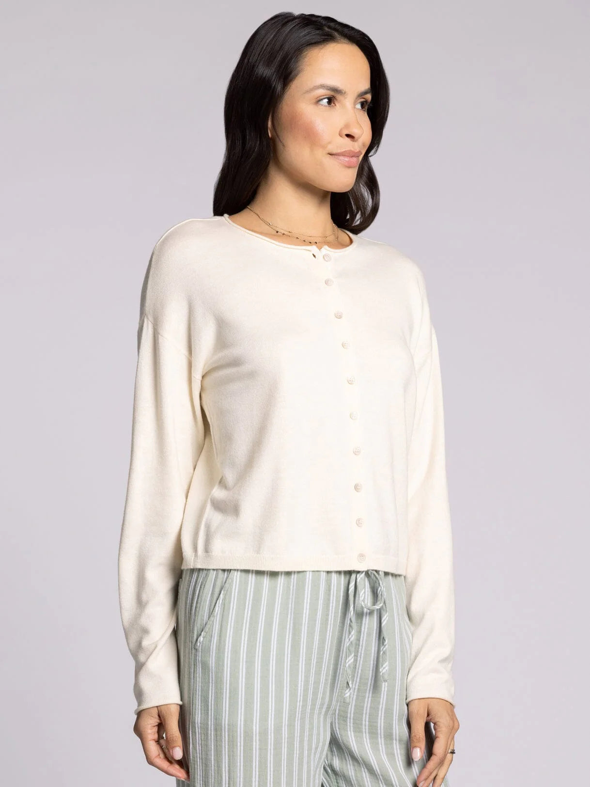Woman wearing ivory cropped knit cardigan sweater with button front and relaxed fit