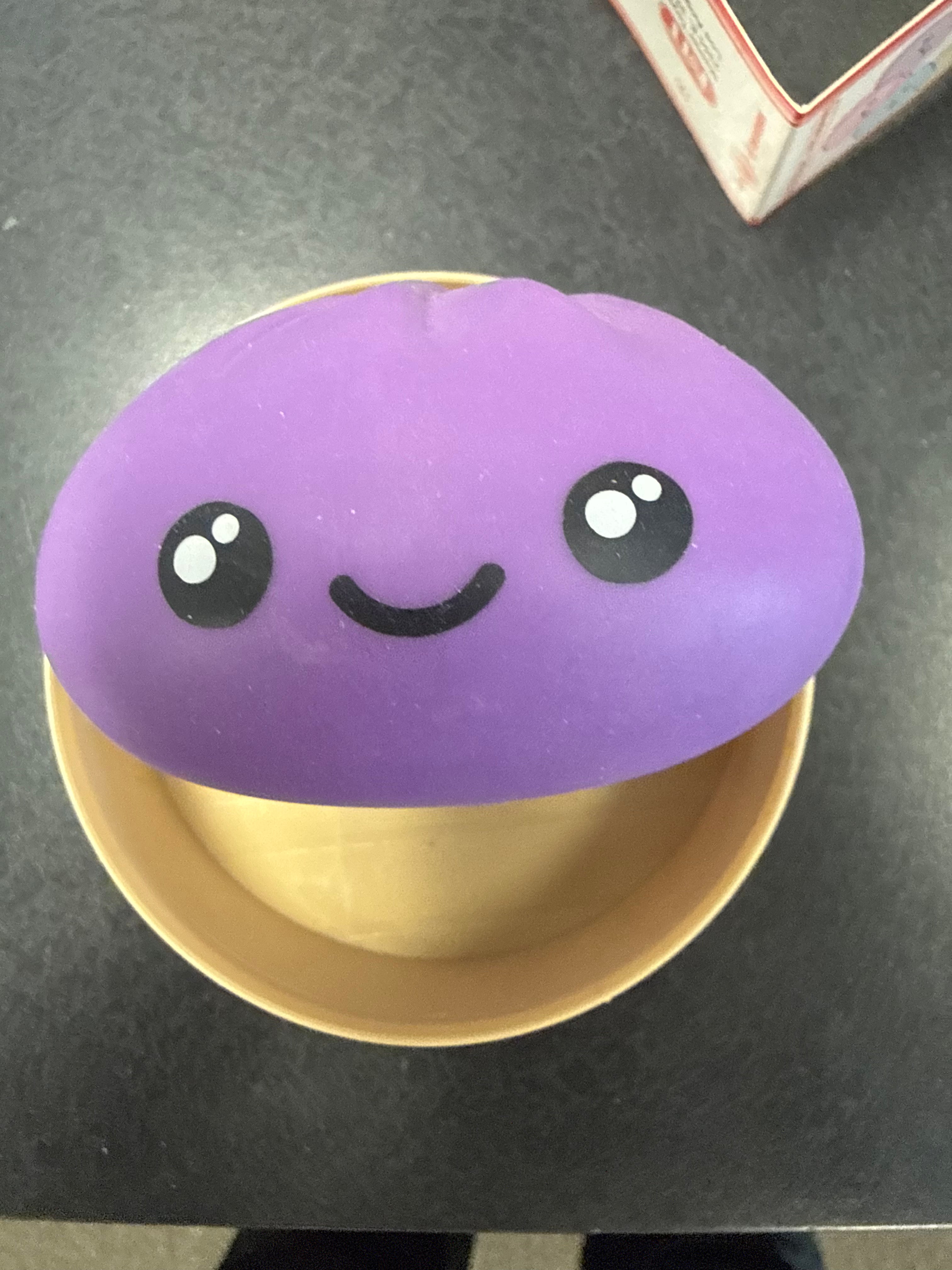 Mystery dumpling squishy sensory toy sitting in container base.