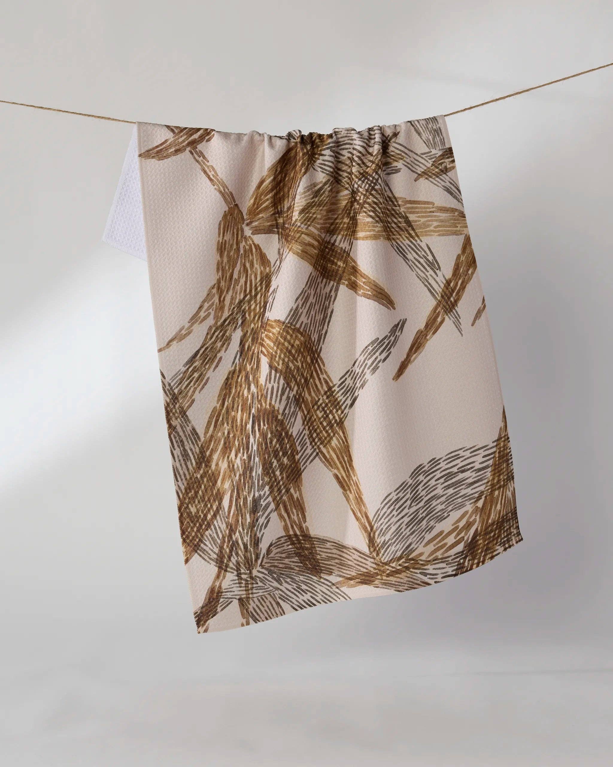Geometry Amber Wildflower Tea Towel — warm off-white Geoweave™ kitchen towel with stylized brown and dark gray brushstroke leaf print, 18x30 inches, made from recycled materials