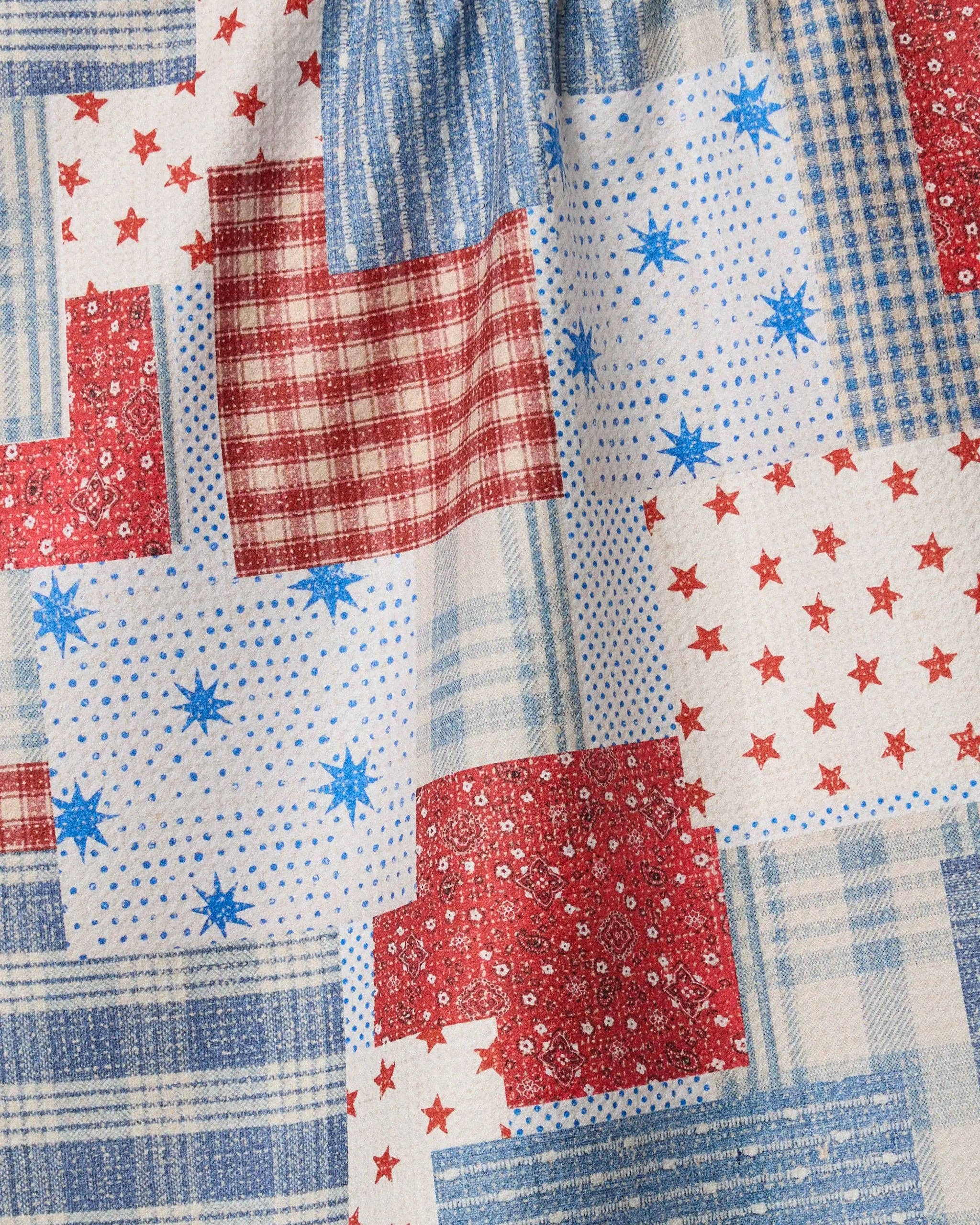 Close-up view Geometry Stars and Stitches tea towel with red, blue, and white patterns