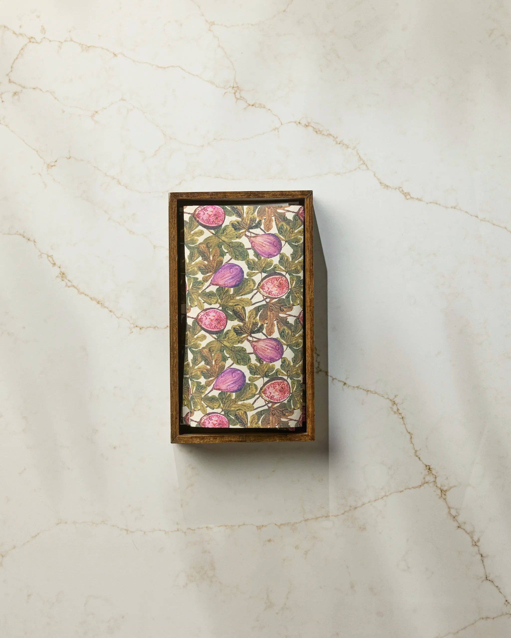 Geometry Wild Fig Not Paper Towel displayed in a dark wood countertop holder on white marble, showing full botanical wild fig print with purple and pink figs — eco-friendly reusable paper towel