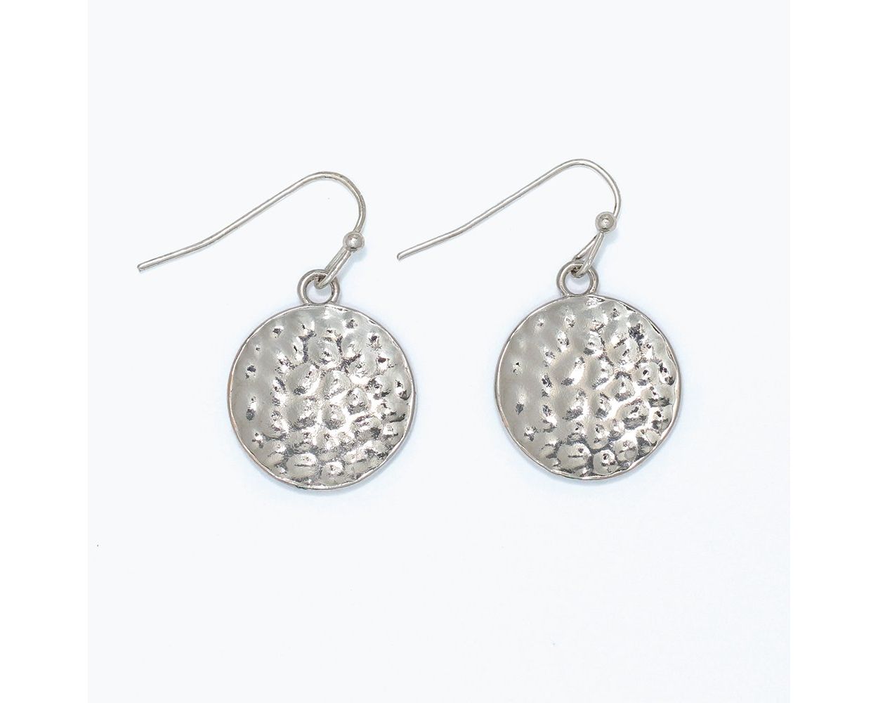 Hammered silver coin disc drop earrings with deeply textured artisan-inspired surface on fishhook wire by Periwinkle — bold yet minimalist silver statement earrings