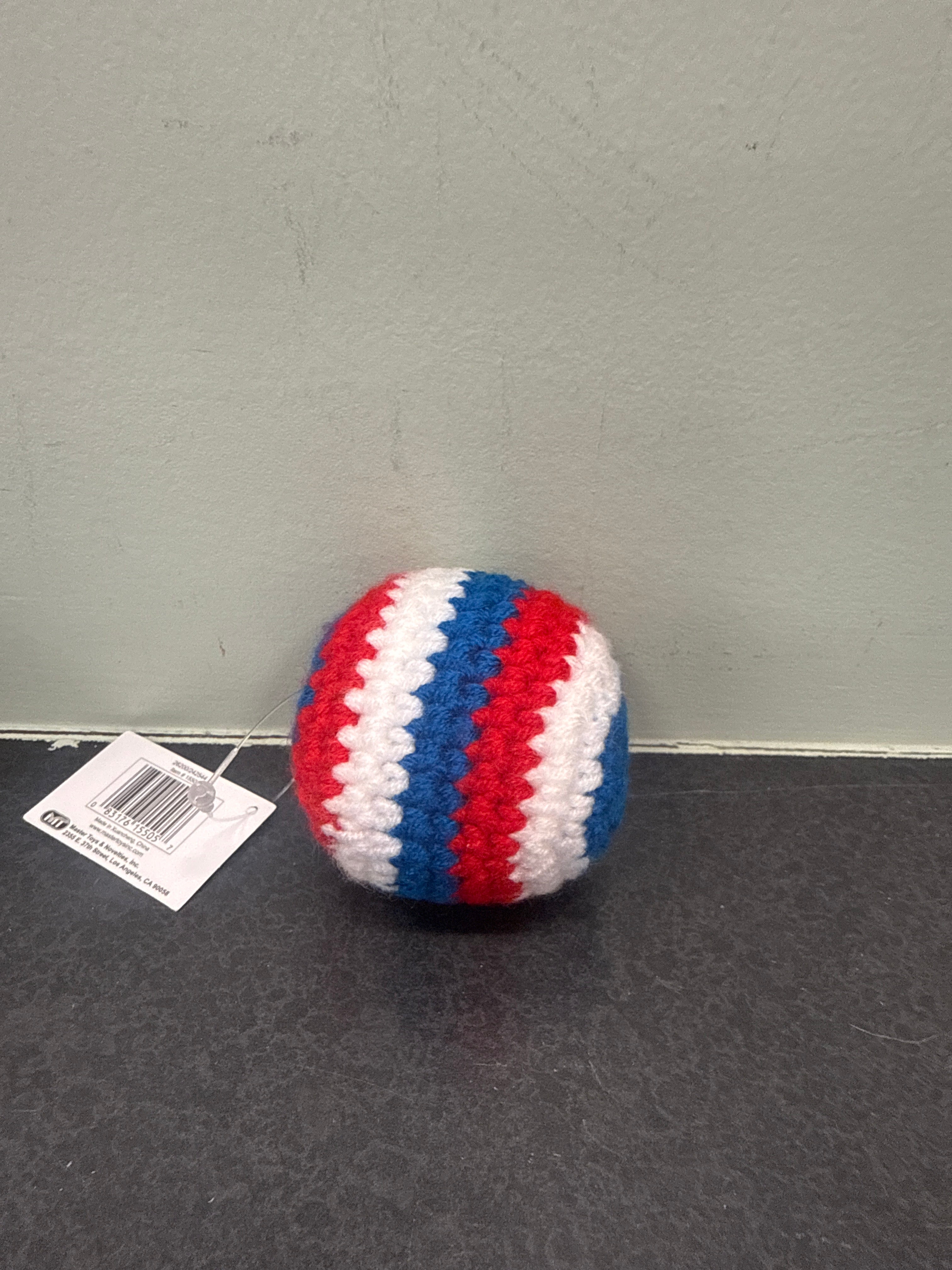 Crocheted kick sack with red, white, and blue stripes on a gray surface