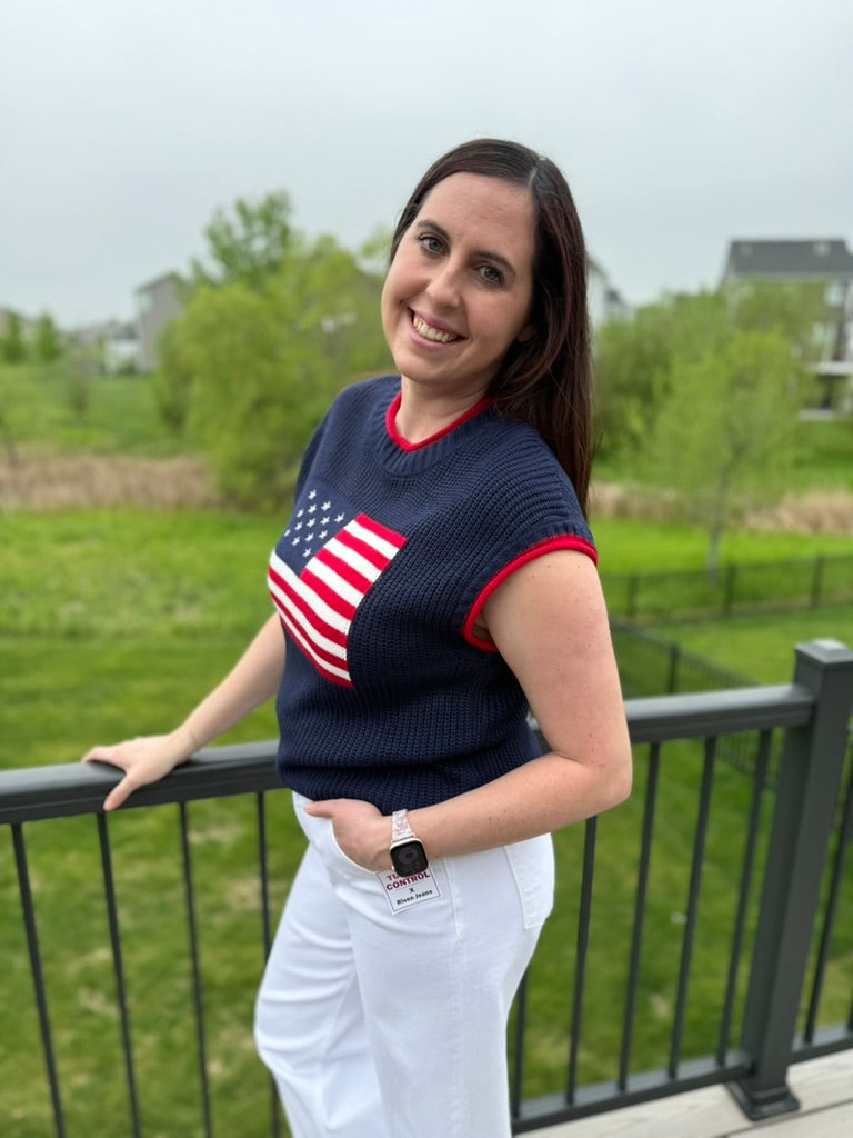 Woman wearing a navy sweater with an American flag design, standing outdoors.