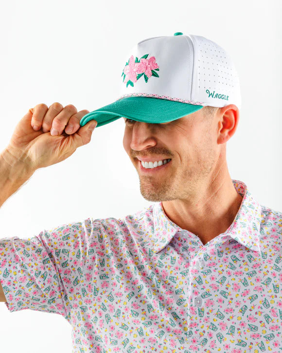 Man wearing a white cap with floral design and colorful shirt on a white background