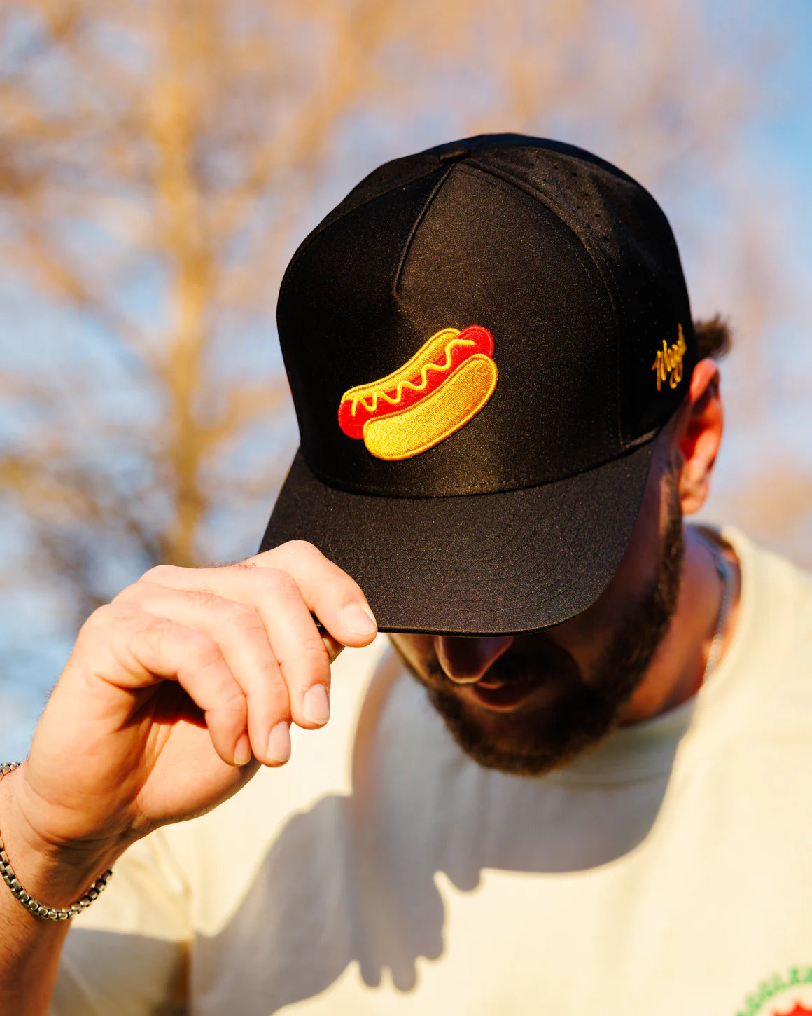 Person wearing Waggle Glizzy snapback hat with embroidered hot dog design on black hat