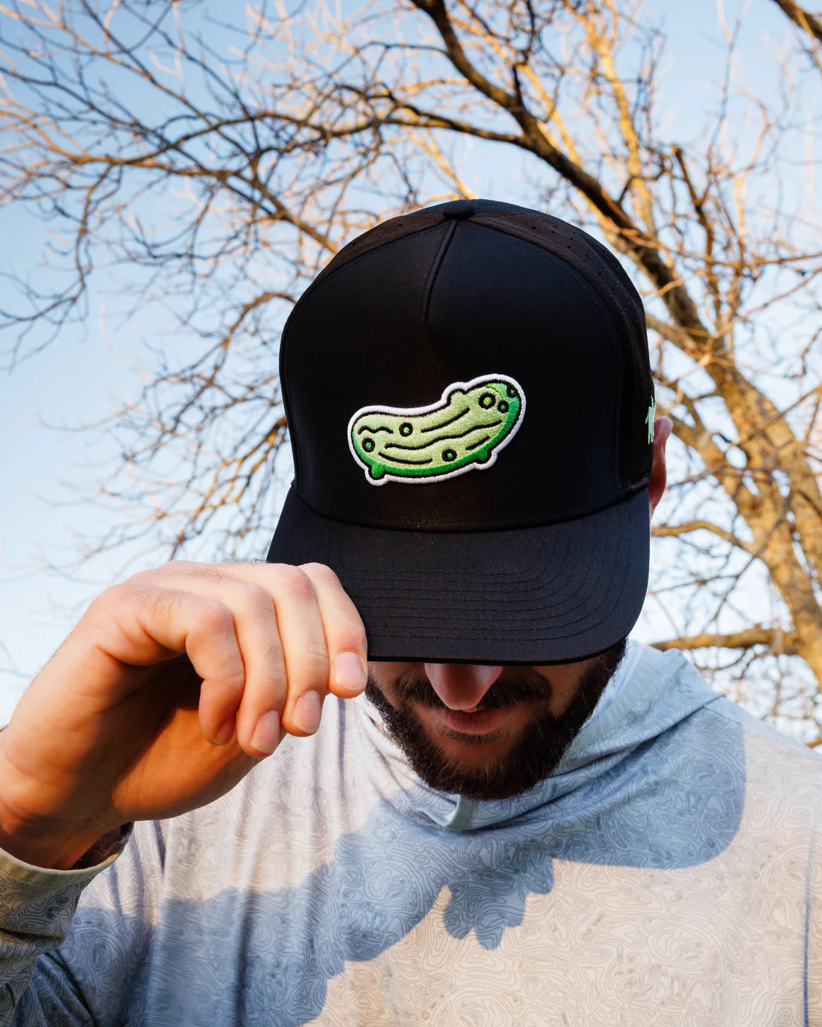 Man wearing Waggle Pickled snapback hat with green pickle design on black hat