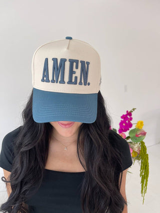 Person wearing a cap with 'AMEN' text against a neutral background