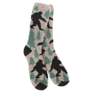 A pair of plush, fuzzy 1902 crew socks featuring a camouflage pattern of green pine trees and black Bigfoot silhouettes on a light beige background.