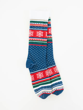 A pair of World's Softest women's crew socks with a blue base featuring white snowflake patterns and red, green, and white striped festive borders, displayed against a plain white background.
