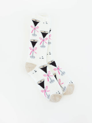 A pair of World's Softest white crew socks with a repeating pattern of black cocktail glasses tied with pink bows, featuring beige heels and toes, displayed on a clean white background.
