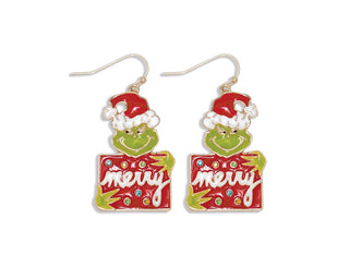 A pair of Grinch-themed Christmas dangle earrings on a plain white background. Each earring features a green Grinch face wearing a red Santa hat above a red sign that says 'Merry' in white script, with small multicolor rhinestone accents.