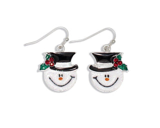A pair of silver-toned dangle earrings shaped like snowman faces wearing black top hats with green holly leaves and red berries, shown on a plain white background.