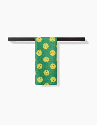 Green towel with yellow floral pattern hanging on a black towel rack against a white background