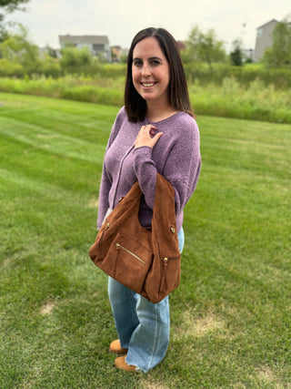 Person holding a brown Heidi faux suede hobo handbag.