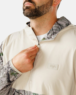 Close-up of Waggle script logo and half-zip pull on cream chest panel of Zenith Hoodie in Treed It camo print