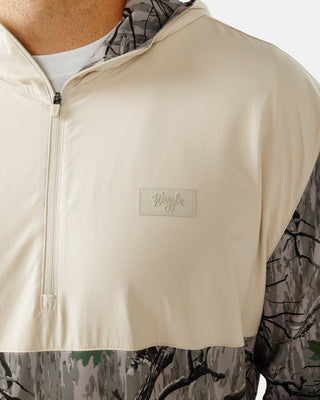 Close-up of embossed Waggle logo patch on cream chest panel of Zenith Half-Zip Hoodie in Treed It camo