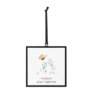 Friends Grow Together Suncatcher by DEMDACO — full view of the square black metal floating frame showing the sea glass butterfly and two sea glass flowers with "friends grow together" sentiment, hung by a black grosgrain ribbon against a white background