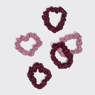 Five ruffled scrunchies in two shades of pink and two shades of deep burgundy, arranged on a light gray background.