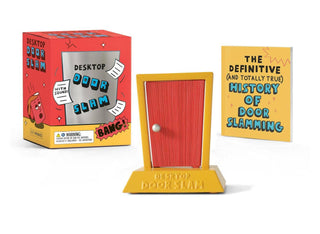 Desk top door slam toy with packaging and book on a white background
