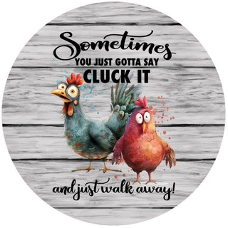 "Cluck It" Silicone Jar Opener by Andréas — round flexible silicone disc with two bug-eyed cartoon chickens on a rustic gray wood-plank background and the humorous text "Sometimes you just gotta say Cluck It and just walk away!"