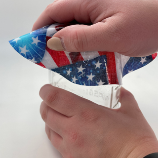Hand holding an American flag-themed jar opener on a white background