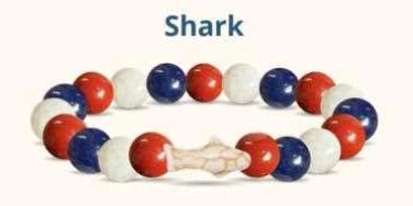 Beaded bracelet with red, white, and blue beads and a shark charm on a white background.