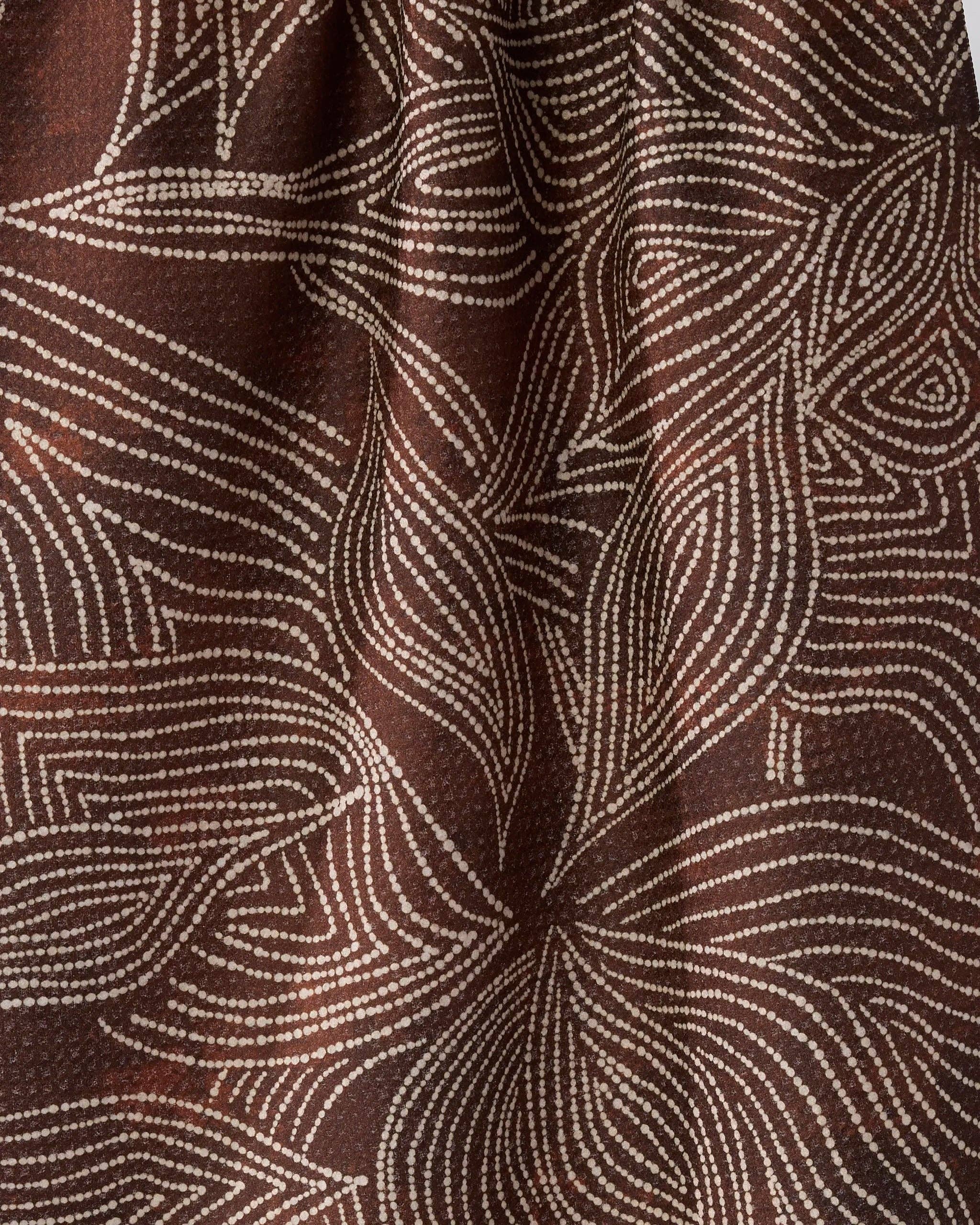 A close-up of Geometry brown textured towel with a white dotted abstract pattern resembling flowing leaves.