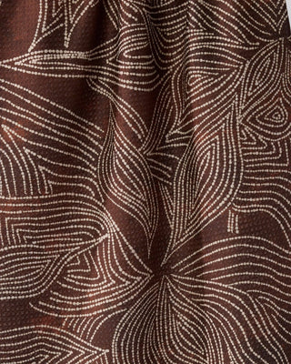 A close-up of Geometry brown textured towel with a white dotted abstract pattern resembling flowing leaves.