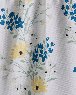 Close-up of Geometry Garden Picks floral kitchen tea towel featuring blue blossoms and yellow flowers on white Geoweave™ fabric