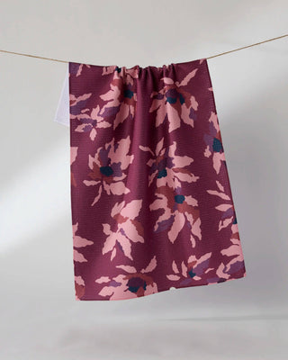 Geometry Mulberry Bloom Tea Towel hanging on a clothesline showing full 18x30 eco-friendly kitchen towel with deep mulberry background and blush pink floral bloom print