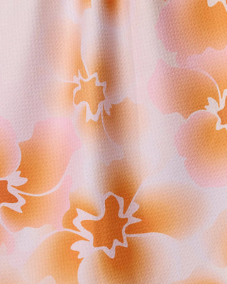 Close-up of a fabric with a floral pattern in orange and white.