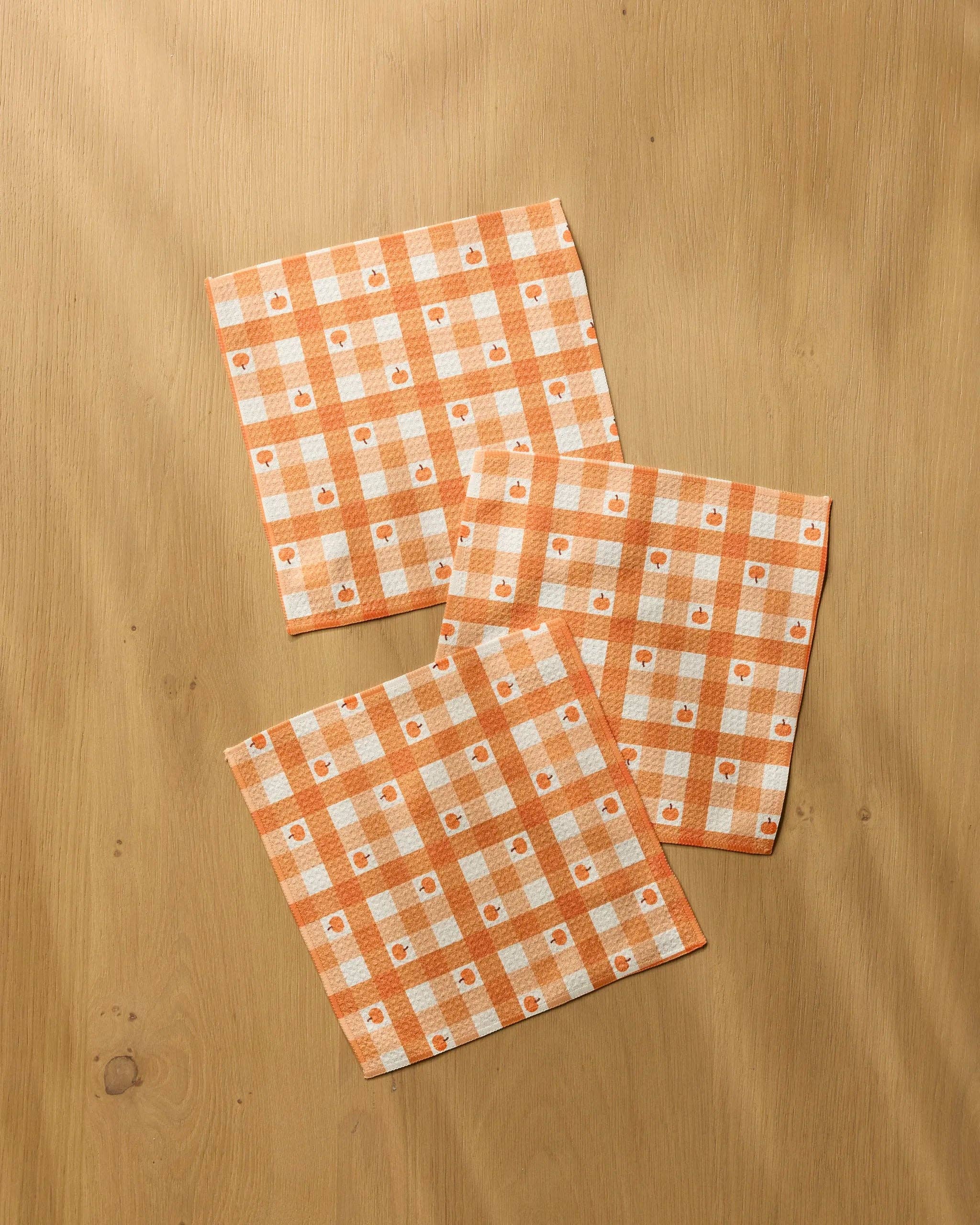 Geometry Pumpkin Check Dishcloth Set 3-pack — orange and white gingham check Geoweave™ dishcloths with small orange pumpkin overlay, 10x10 inches each, made from recycled materials
