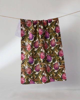 Geometry Wild Fig Tea Towel hanging on a clothesline showing full 18x30 eco-friendly kitchen towel with lush botanical print of purple figs and green leaves on cream background
