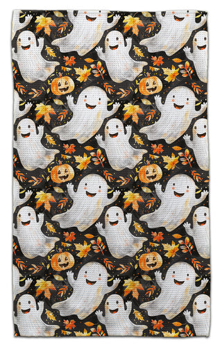 Halloween kitchen towel featuring smiling ghosts, pumpkins and colorful autumn leaves on a black background
