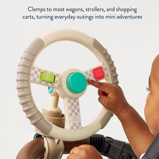 Child playing with a bitzy driver steering wheel attached to a vehicle, with text about clamping to wagons and strollers.