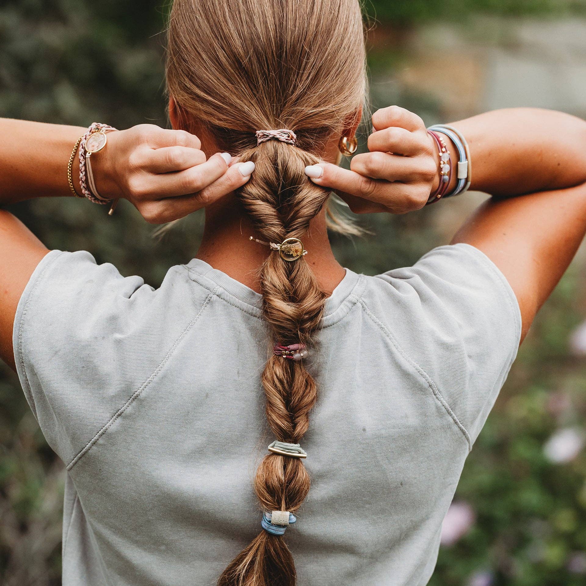 Person wearing Klani Bloom hair tie bracelet set with pink, maroon, gold accents, and pressed flower details