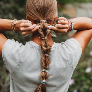 Person wearing Klani Bloom hair tie bracelet set with pink, maroon, gold accents, and pressed flower details