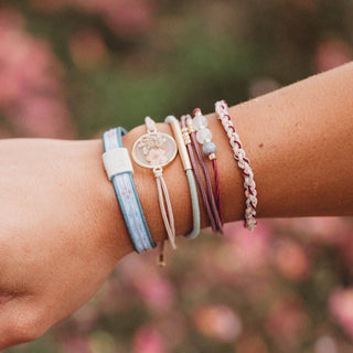 Close up view of Klani Bloom hair tie bracelet set with pink, maroon, gold accents, and pressed flower details