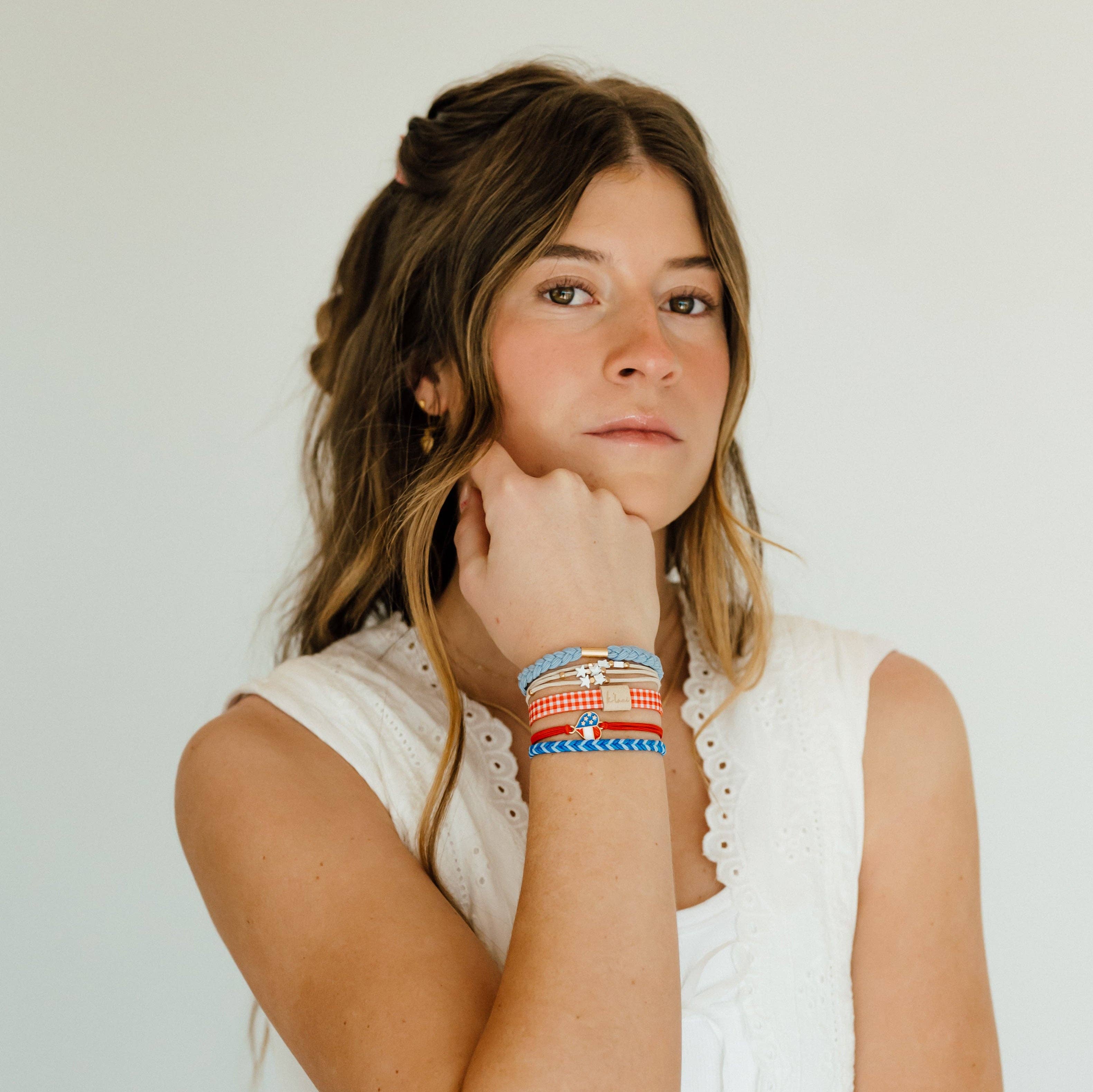 Women wearing K’lani Free patriotic hair tie bracelet set in red, white and blue with USA heart charm and gingham accent on her wrist