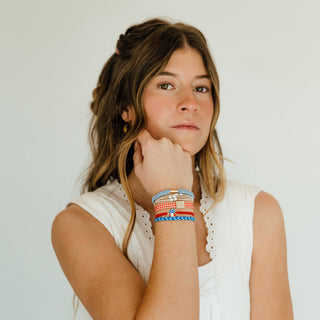 Women wearing K’lani Free patriotic hair tie bracelet set in red, white and blue with USA heart charm and gingham accent on her wrist
