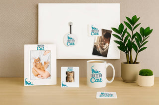 Collection of 'Better Cat' branded products including frames, a mug, and coasters on a desk.