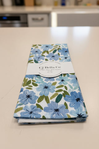 Eco-friendly waffle weave kitchen towel featuring delicate watercolor light blue flowers with green leaves on a white background.