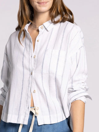 Woman wearing a white striped shirt with rolled-up sleeves on a plain background