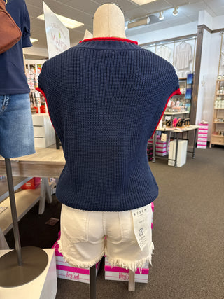 Mannequin wearing a navy sweater with red trim in a store setting