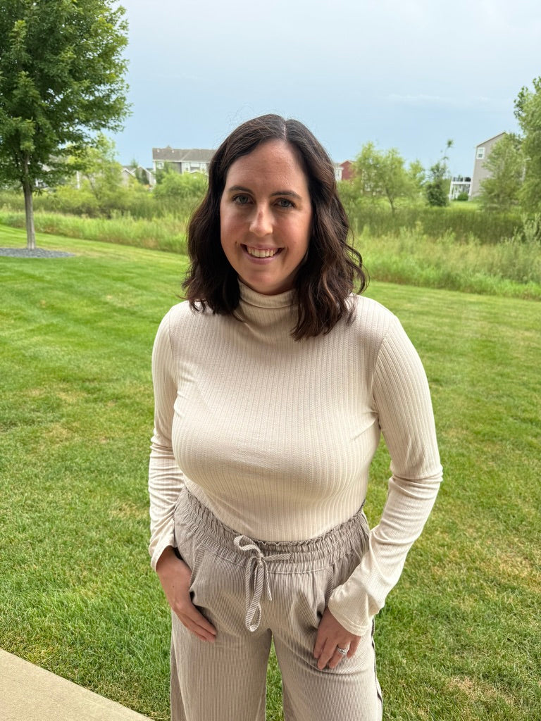 A women wearing a pointelle Mock Neck Top features a delicate pointelle and ribbed knit construction with a fitted silhouette that layers beautifully under jackets, vests, or on its own