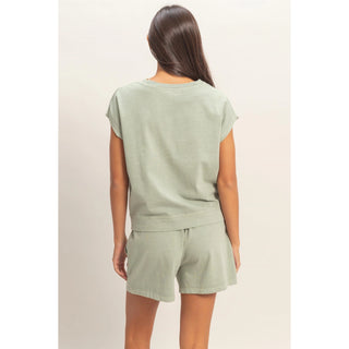 woman wearing sage green cotton sleeveless top and matching shorts set with pockets back view