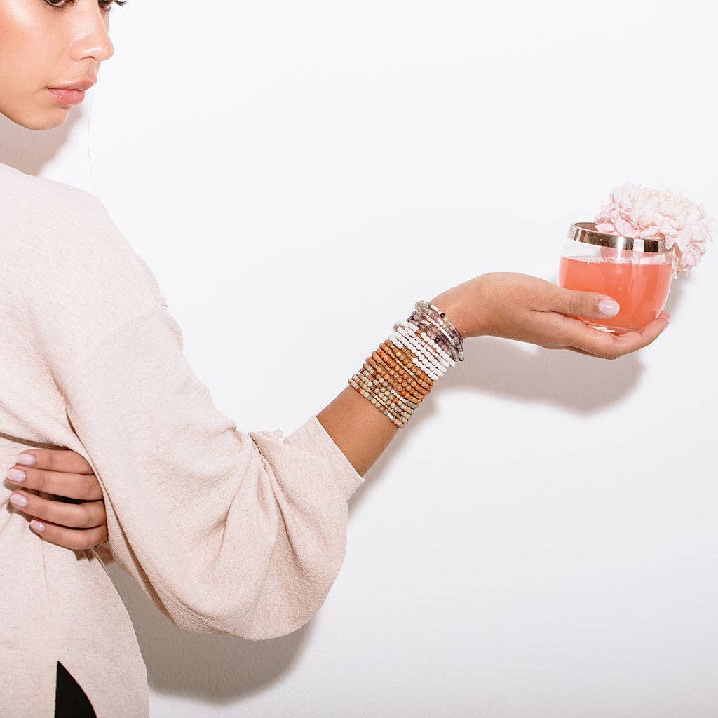 Woman wearing multiple bracelets on a white background