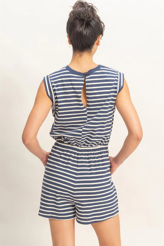 woman wearing navy striped sleeveless romper with drawstring waist and pockets back view